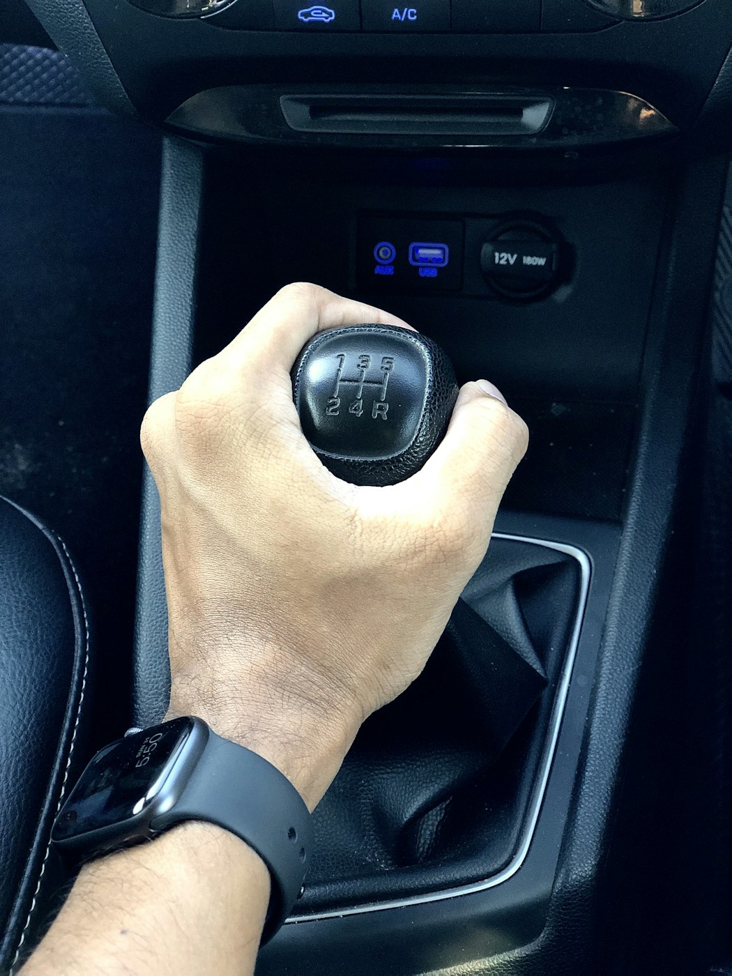 Eine Hand liegt auf dem Schaltknauf eines Autos mit Handschaltung